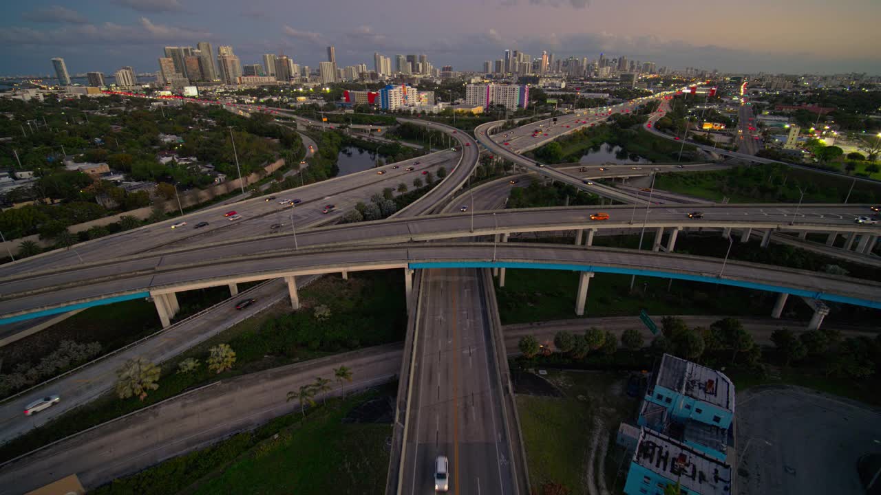在北迈阿密，95号州际公路和I-195号公路之间繁忙的高架交通枢纽，日落时分，用超宽镜头拍摄的迈阿密市区和设计区远处的景象。无人机拍摄的前移镜头。视频素材
