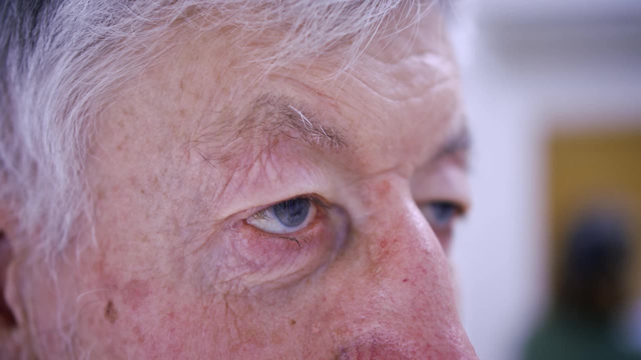 一个老人凝视远方的特写。灰头发，蓝眼睛，睿智的眼神。视频下载