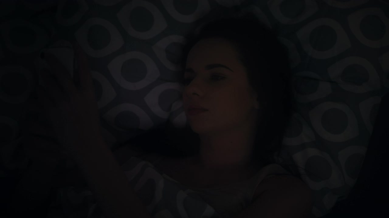 女人使用手机，晚上在家里的床上睡觉视频下载
