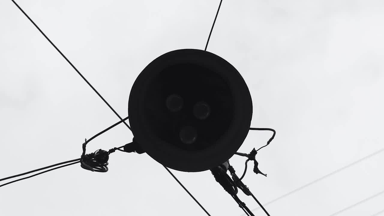 三盏钨丝灯的老式街灯挂在电缆上，背景是灰色的天空。自底向上的视图。视频下载