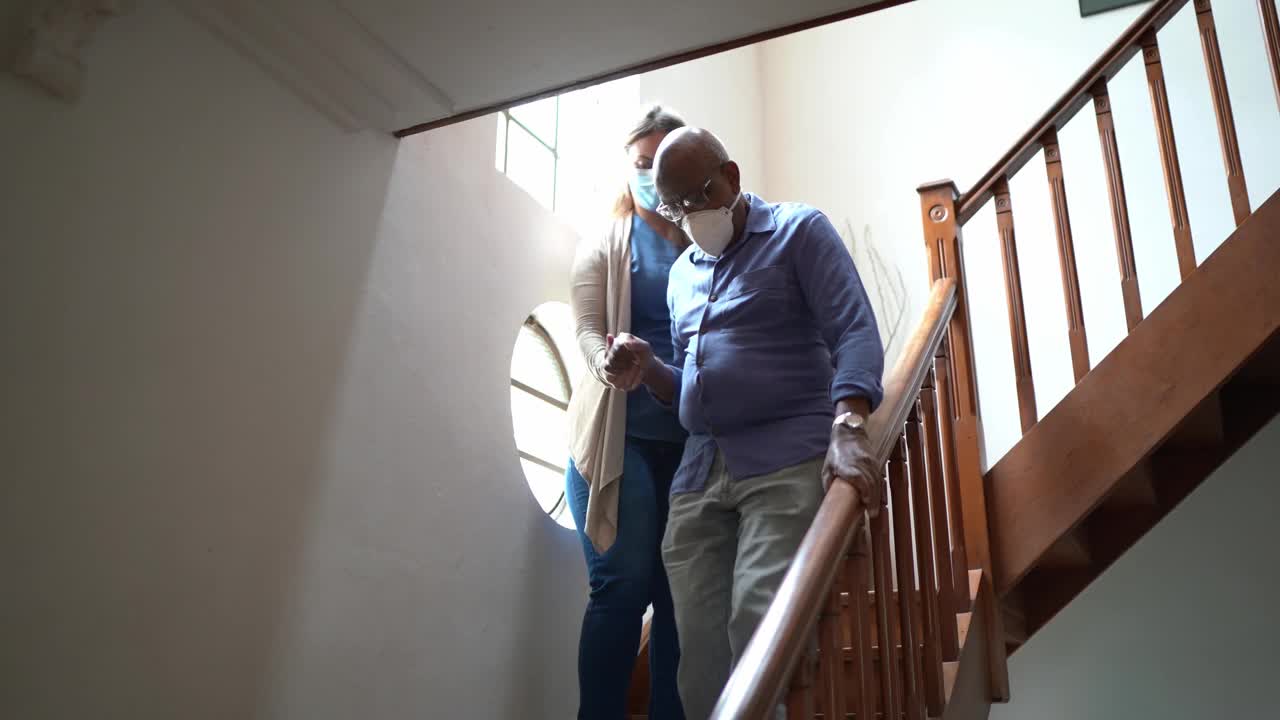 家庭护工帮助老人在星上行走，戴着口罩在家视频素材