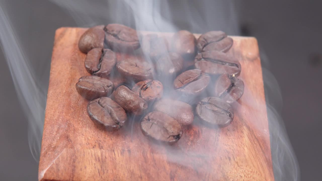 烤咖啡豆与烟在黑色的背景特写。有选择性的重点视频下载