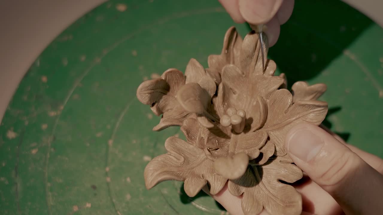 特写的陶工的手覆盖着粘土，使美丽的花在扔轮在陶器车间。创意和传统工艺概念。制造陶瓷制品的材料。视频下载
