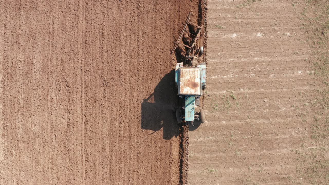 顶部鸟瞰图的拖拉机犁地在农业农田。视频下载