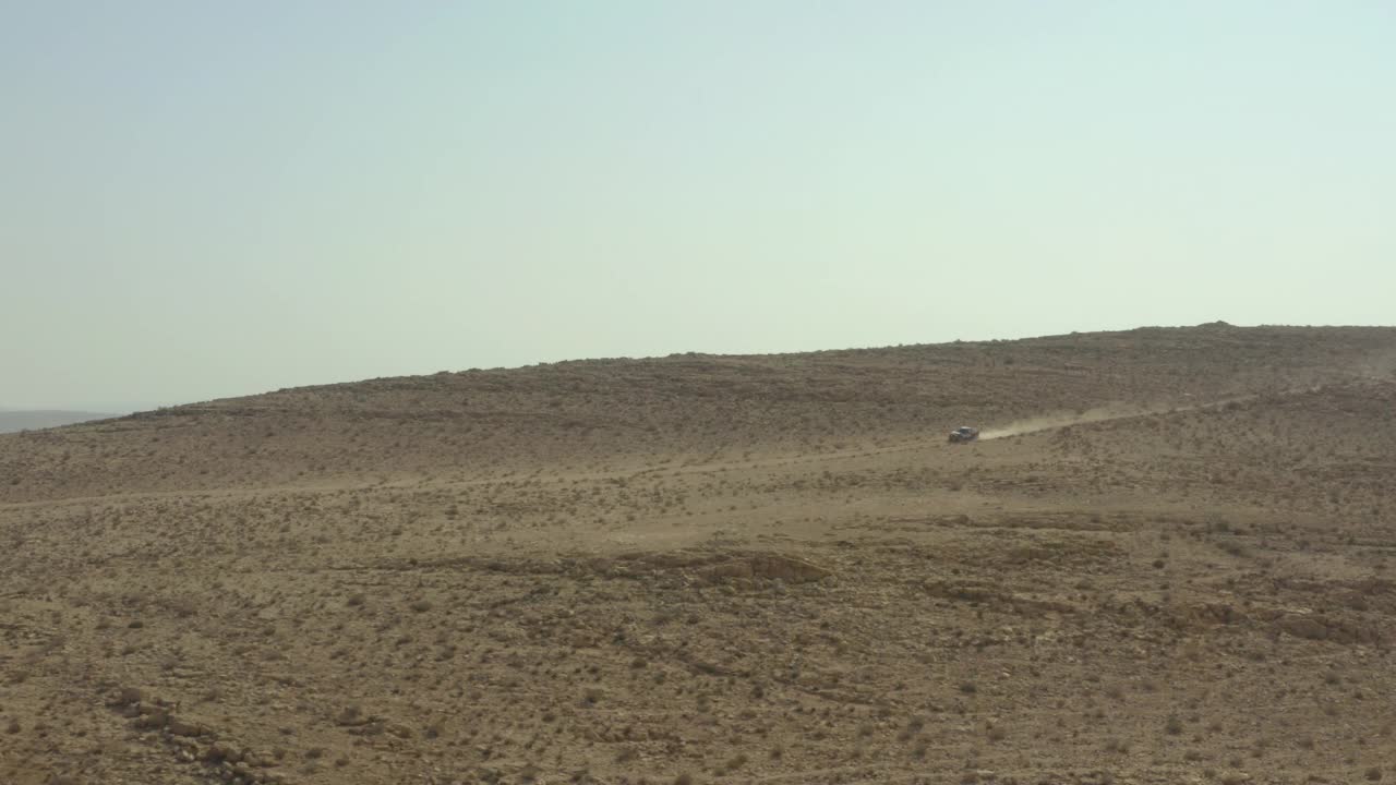 空中摇摄越野车辆在落基山下坡，无人机在沙漠中灌木丛中的岩石上飞行-内盖夫，以色列视频素材