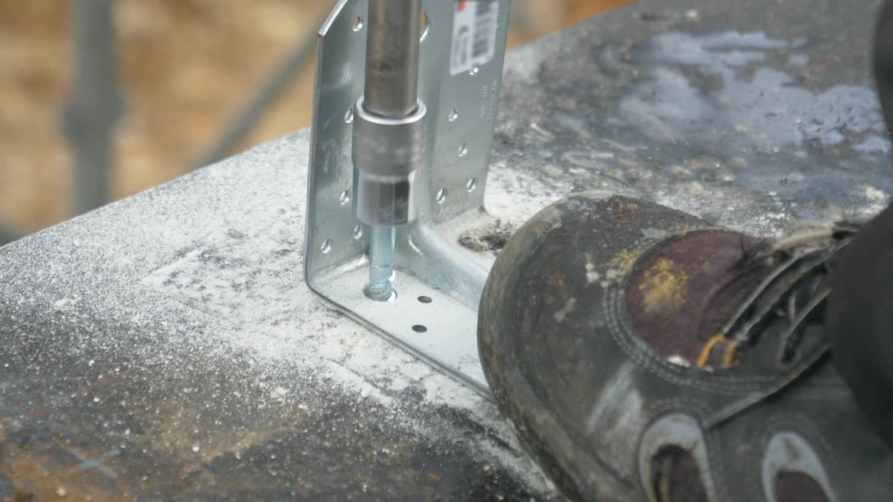 特写:建筑者用电钻将螺栓固定在混凝土地基上。视频下载