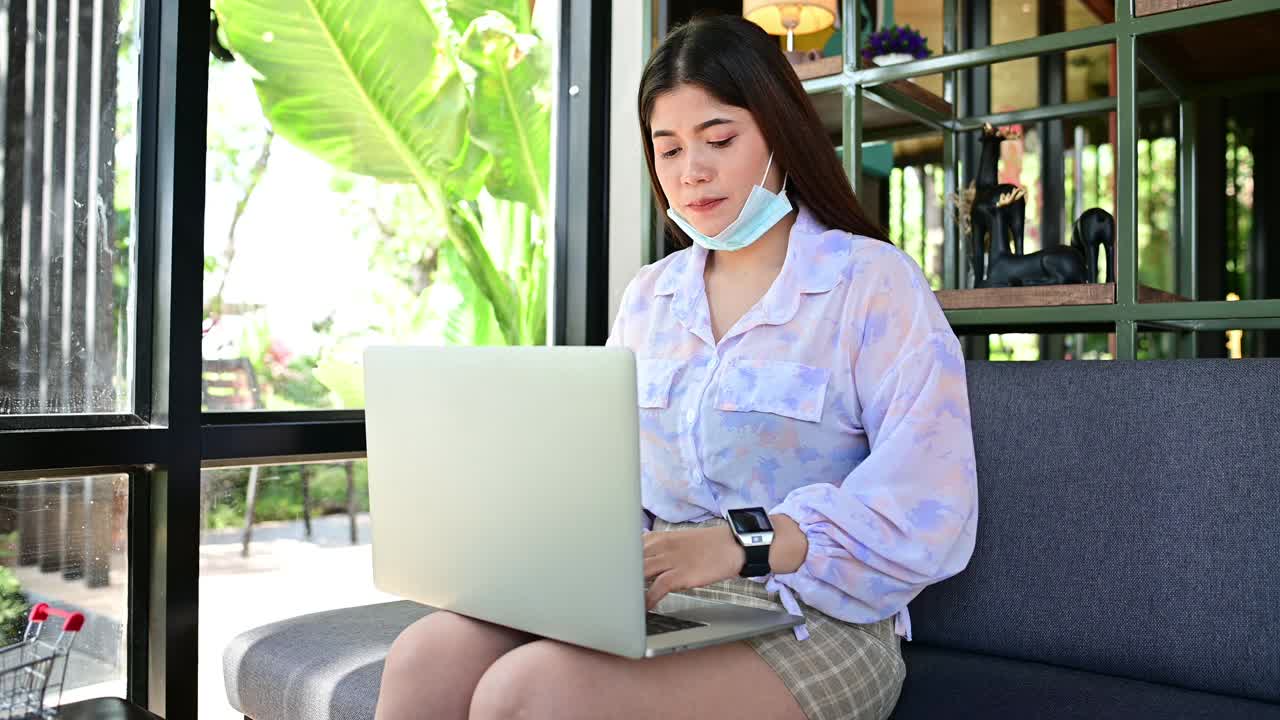 亚洲女性通过笔记本电脑和手表看工作时间视频素材