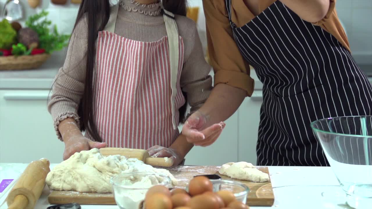 亚洲母亲和女儿正在互相帮助做面包或在厨房里烤的乐趣。反映了母亲对女儿的爱。视频下载