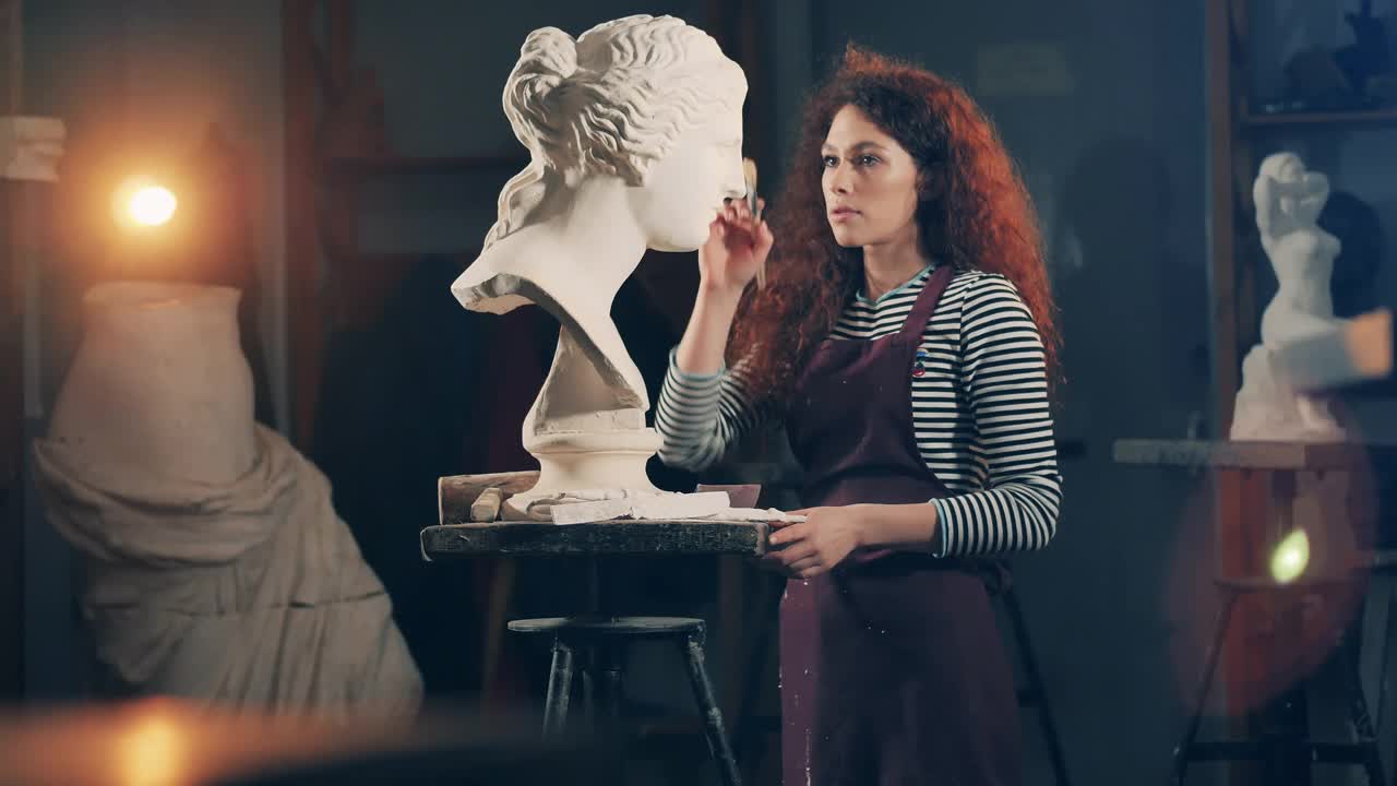 女雕刻家正在照料一个白色的石膏半身像。灵感、创意的工作理念。视频下载