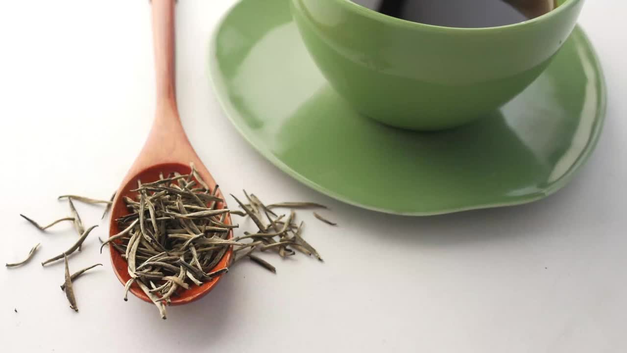 俯视图的绿茶和草药叶在一个小玻璃碗在桌子上视频下载