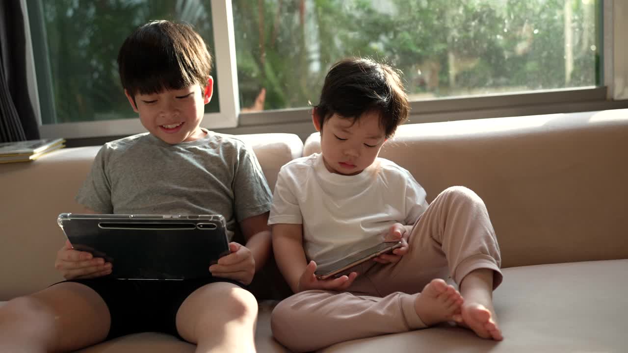 一个兄弟叫他的弟弟看他的平板电脑，表达了兄弟们分享的爱视频下载
