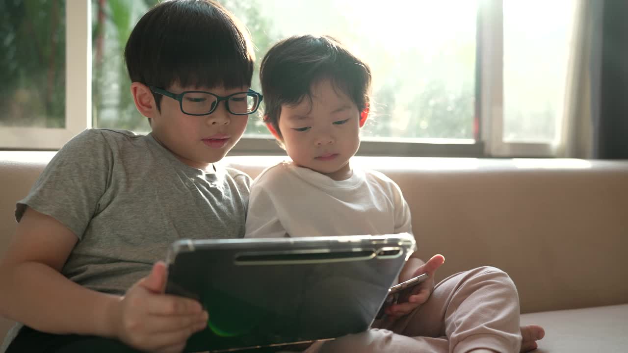 一个兄弟叫他的弟弟看他的平板电脑，表达了兄弟们分享的爱视频下载