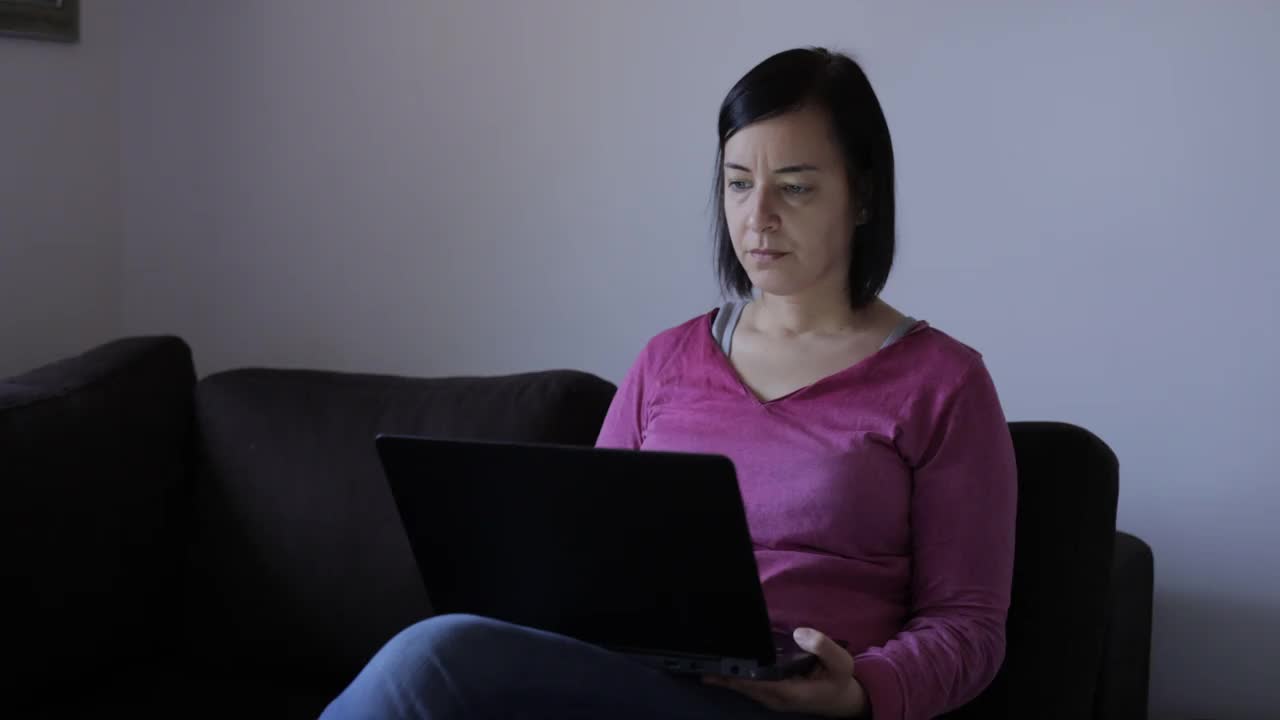 一位女士正在用笔记本电脑在家工作视频下载