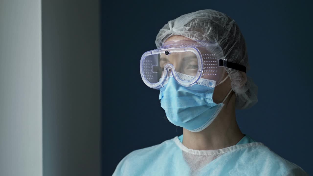 疲惫的女医生或护士的肖像。这个女人摘下了她的护目镜和面具，松了一口气。大流行Covid-19视频下载