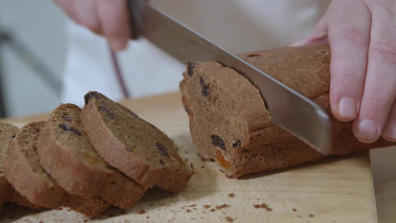 面包师正在用面包刀切新鲜出炉的荷兰葡萄干杯形蛋糕视频下载