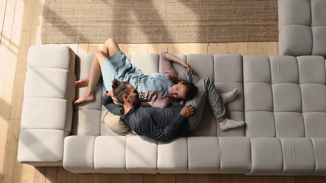 轻松年轻的夫妻躺在沙发上。视频下载