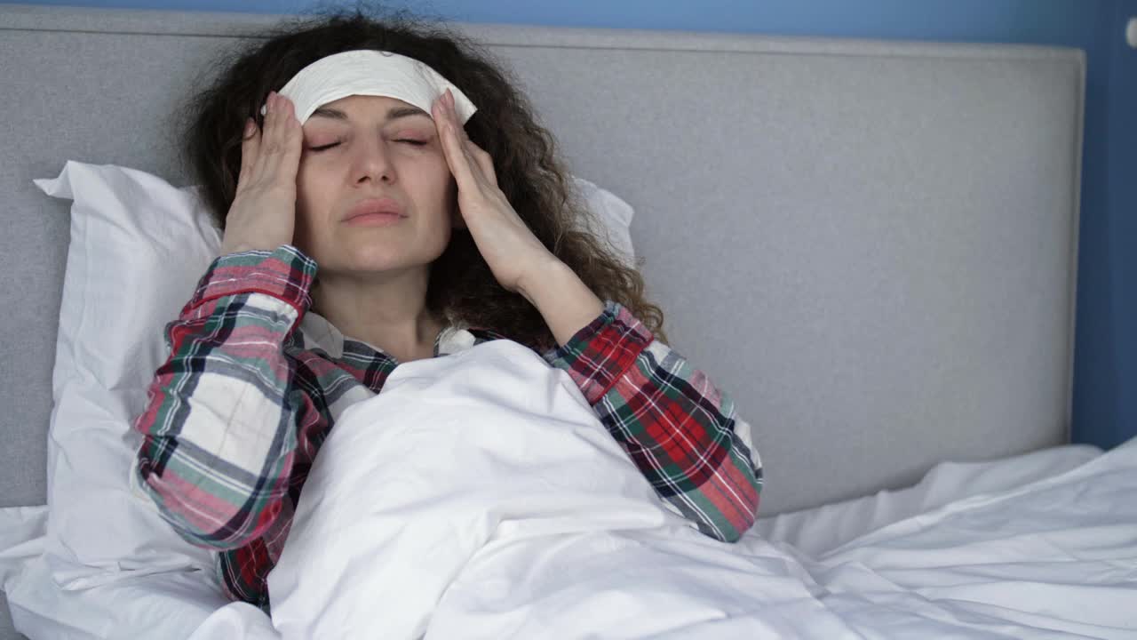 一个生病的女人的肖像头痛和抱一个冷湿敷在她的前额。偏头痛、宿醉或高烧视频下载
