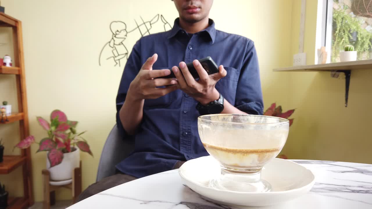 男性喝脏咖啡杯和使用手机视频下载