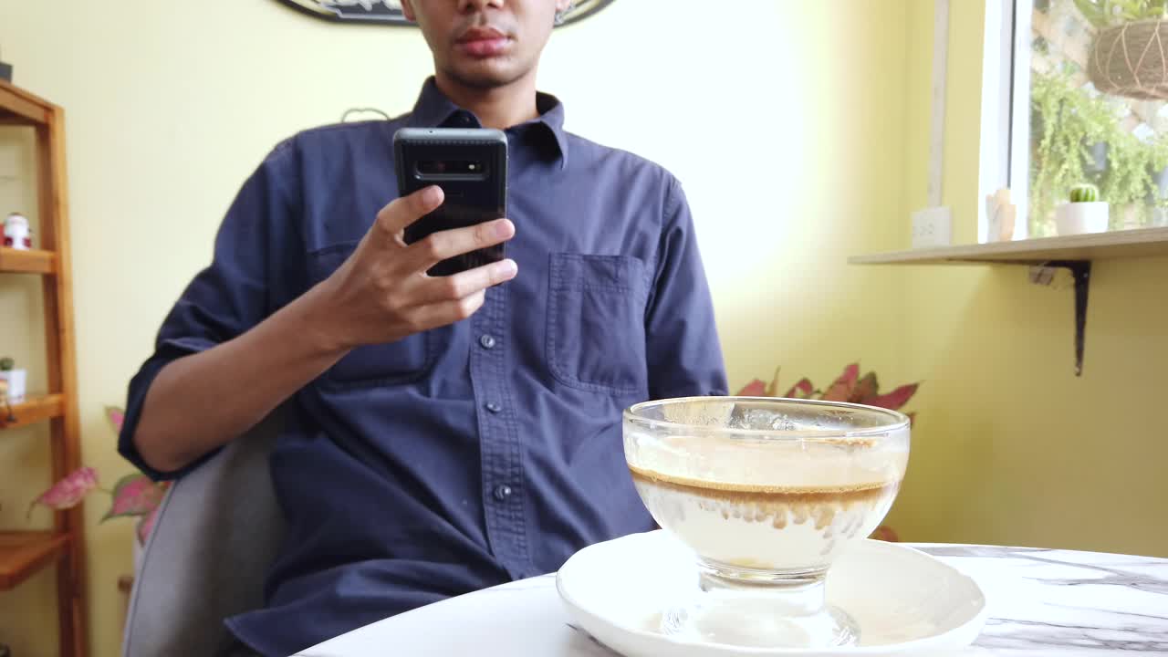男性喝热的脏咖啡杯和使用手机视频下载