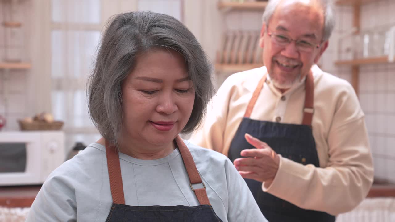 老夫妇在厨房做饭时愉快地聊天。它代表了他们俩永恒的爱。退休后的幸福视频下载