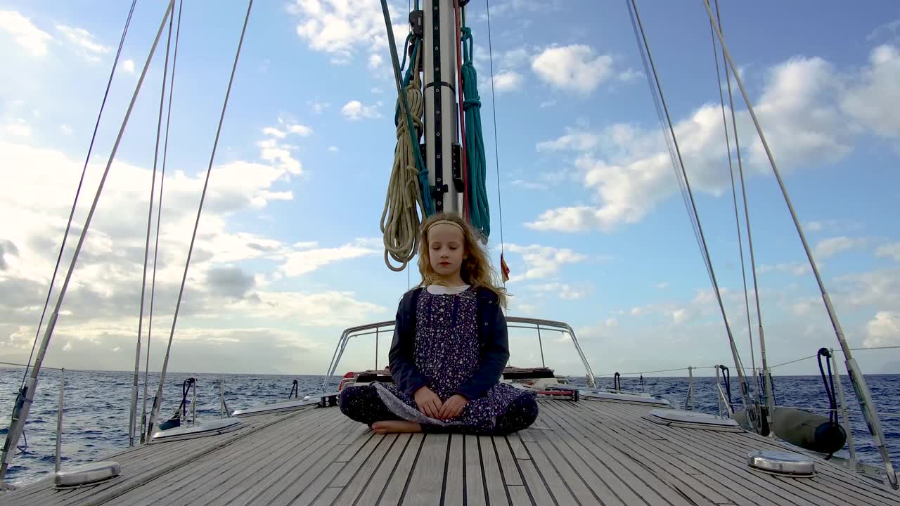 在西班牙加那利群岛附近，一个女孩坐在一艘帆船的甲板上看日落时的大西洋视频下载