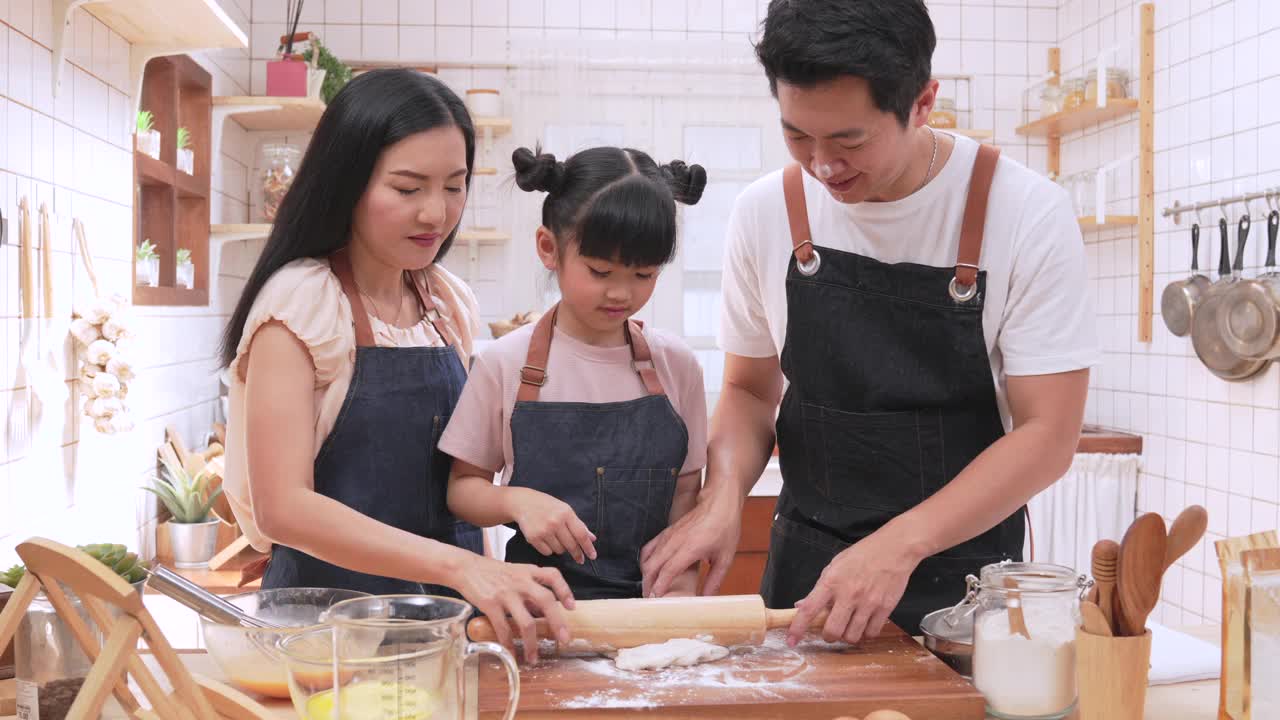 一个温暖的家庭，父母和女儿们在厨房里烤制着，快乐地烤制着。它代表了家人一起度过的时光。视频下载