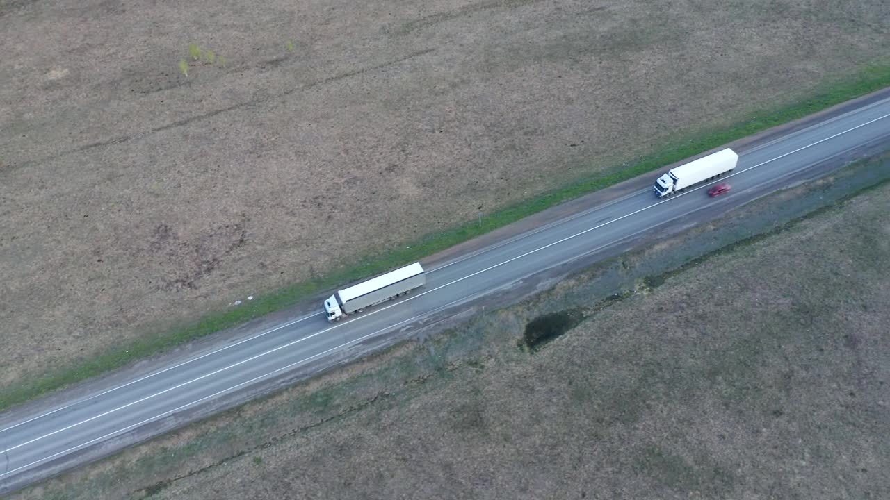 长途过境的概念。两辆载着货物的白色卡车在高速公路纵队上行驶。线路开发，配送组织，物流。视频下载