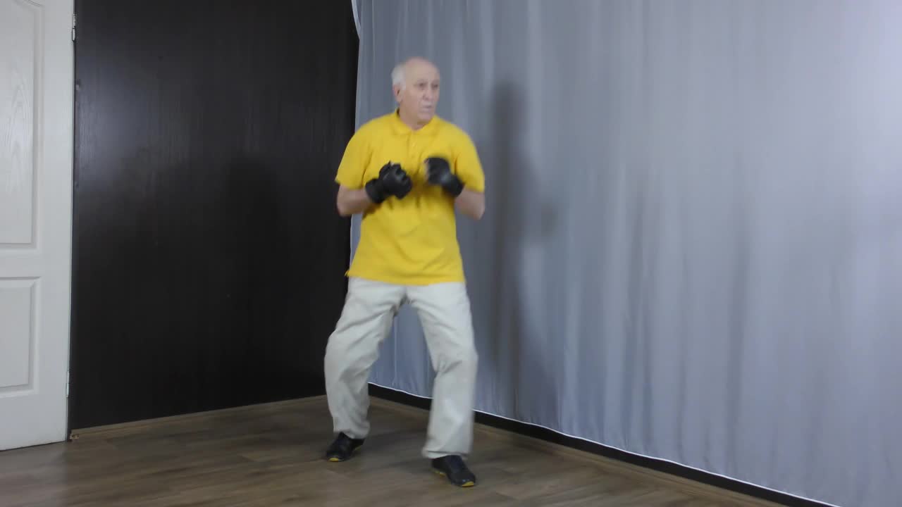 一个老运动员用手在白色背景附近的黑色垫子上打拳视频下载