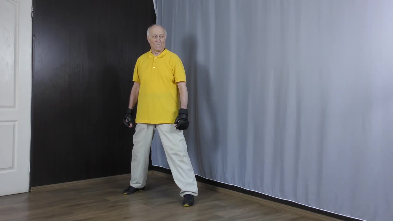 老人运动员用手在接近白色背景的黑色垫子上表演出拳视频下载