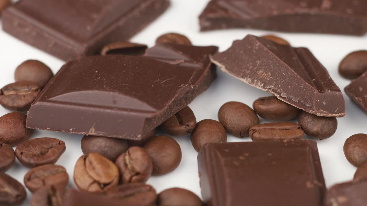 一块巧克力和咖啡豆在一个白色的孤立的背景视频下载