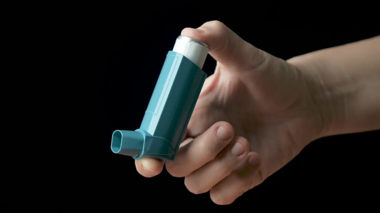 女性手表演哮喘泵示范。黑色背景。视频下载