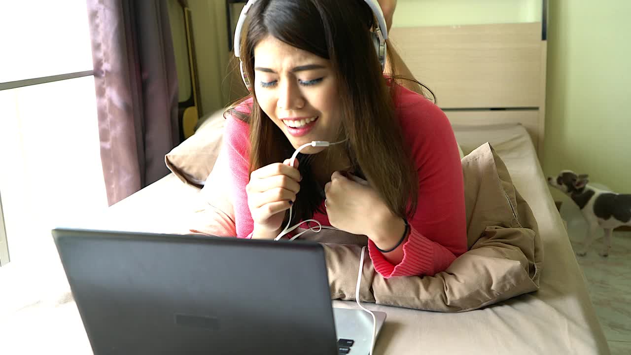 一个年轻女孩或青少年正在通过一个笔记本与某人交谈。通过她房间里的屏幕展示了现代科技在日常生活中的运用。视频下载