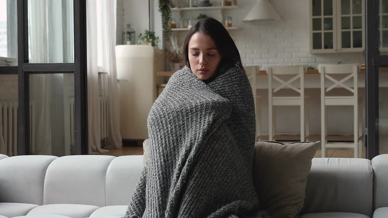 女人裹在温暖的针织格子在寒冷中颤抖视频下载