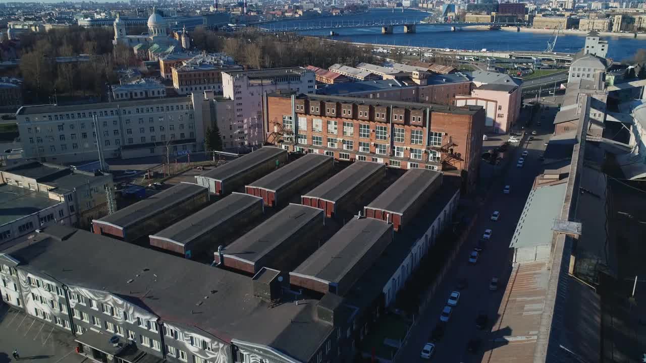 从空中俯瞰，这是俄罗斯圣彼得堡的一个工业区，有工厂建筑和仓库。远离市中心的居民区和偏远地区。现代城市的航空摄影。在背景中，在远处，你可以看到视频素材