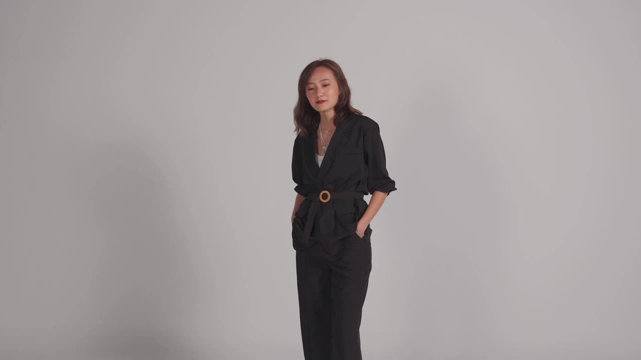 亚洲中国美丽的女人站在口袋微笑与灰色的背景工作室拍摄视频素材