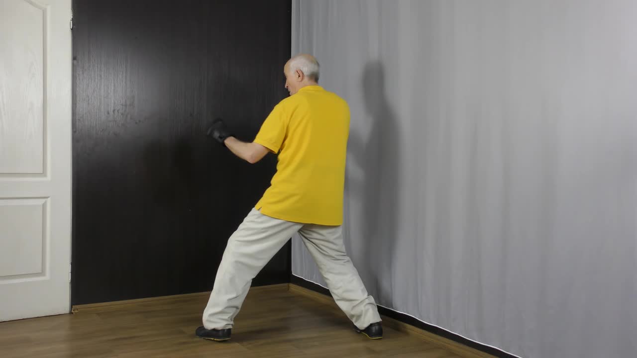 一位手戴黑色护垫的老人运动员在架子上训练动作和出拳视频下载