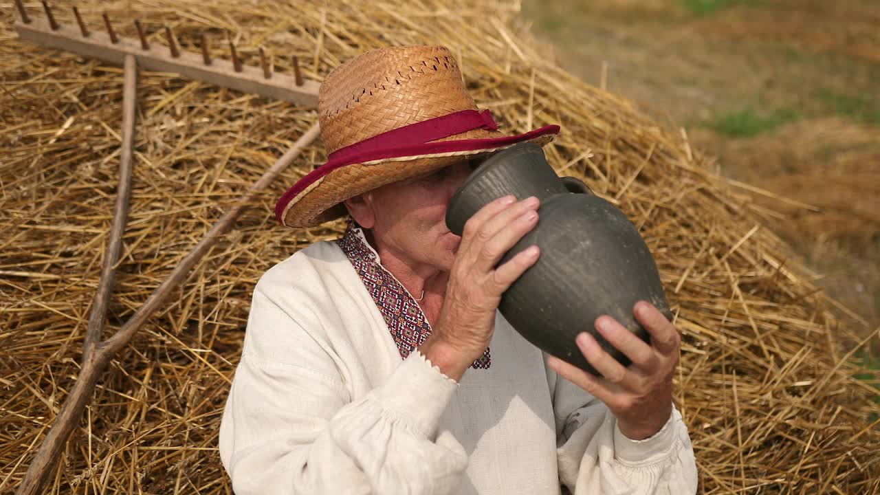干渴的老爷爷从水壶里喝水。戴草帽的男人是疲惫的劳动视频下载