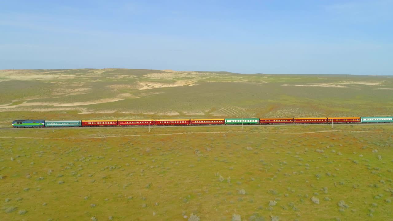 空中向后拍摄的火车行驶在自然景观中的晴天-阿什哈巴德，土库曼斯坦视频下载