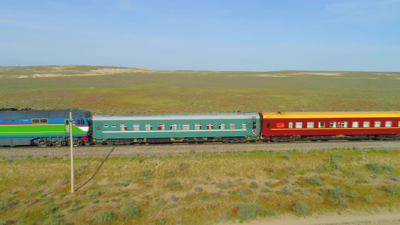 空中向后拍摄的美丽的火车在轨道上行驶在晴朗的一天自然土地-阿什哈巴德，土库曼斯坦视频下载