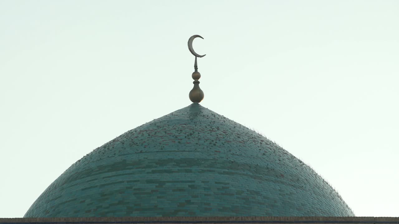 乌兹别克斯坦布哈拉，晴朗的天空下，新月在清真寺圆顶上的封闭特写镜头视频下载