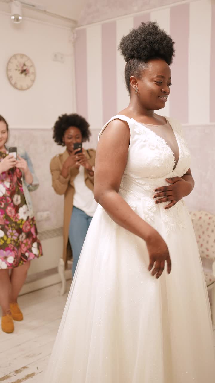 女人试穿婚纱与女性朋友有乐趣和拍照。视频下载