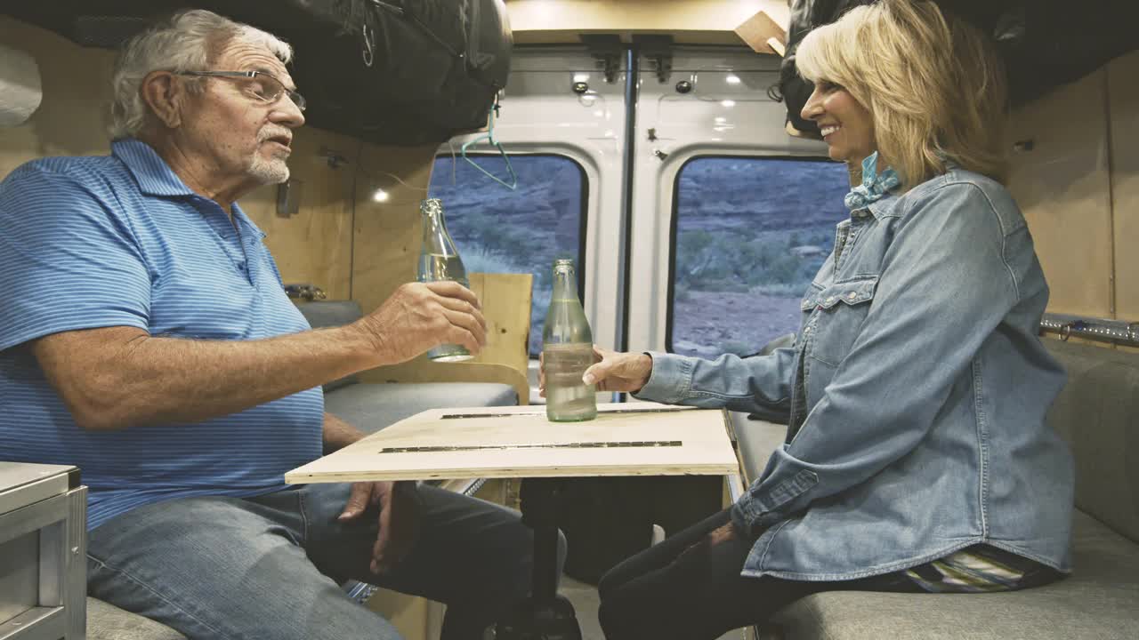 微笑的老年夫妇放松在他们的露营车后在犹他州的一个美好的徒步旅行，近距离，移动的视频剪辑视频下载