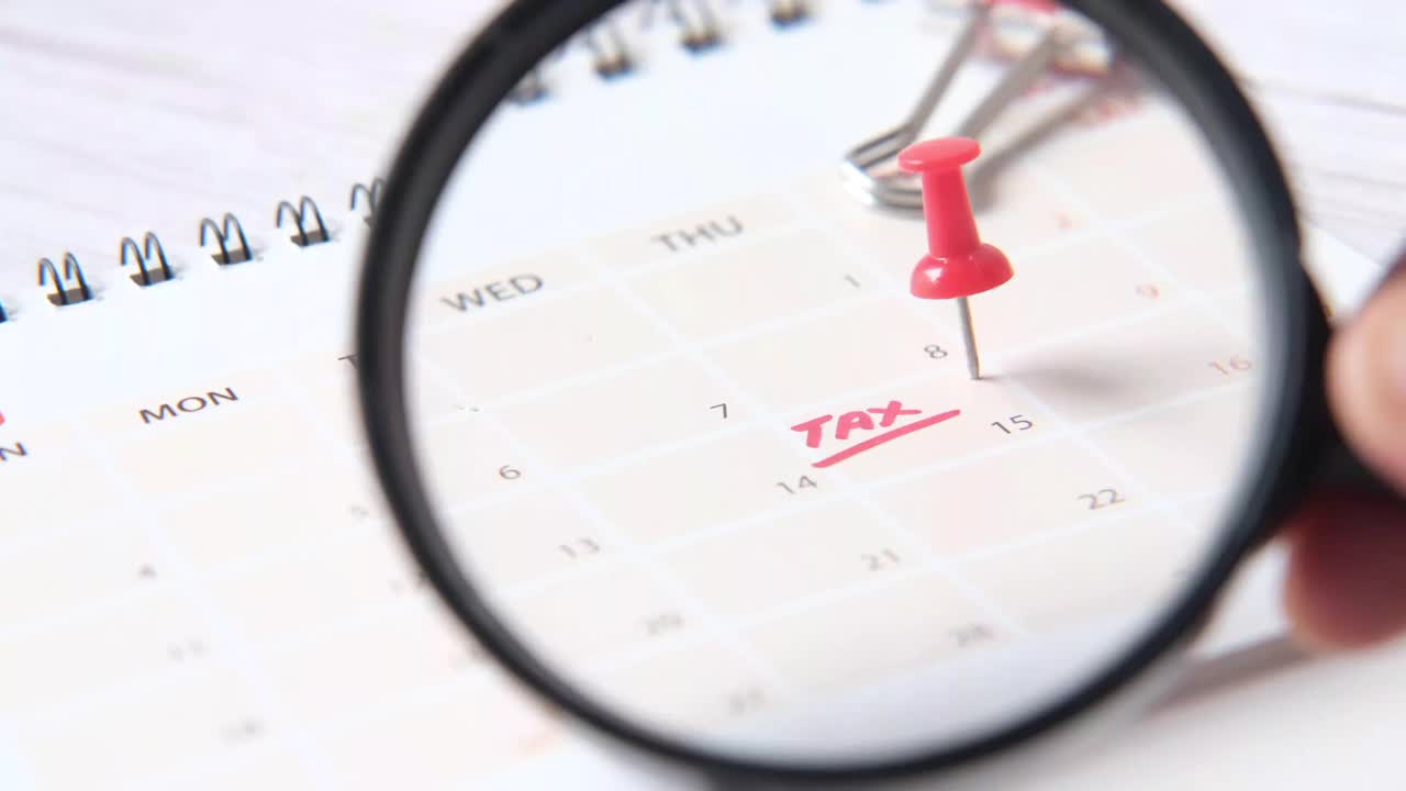 税务日概念与持有放大镜和税务字在日历日期视频下载