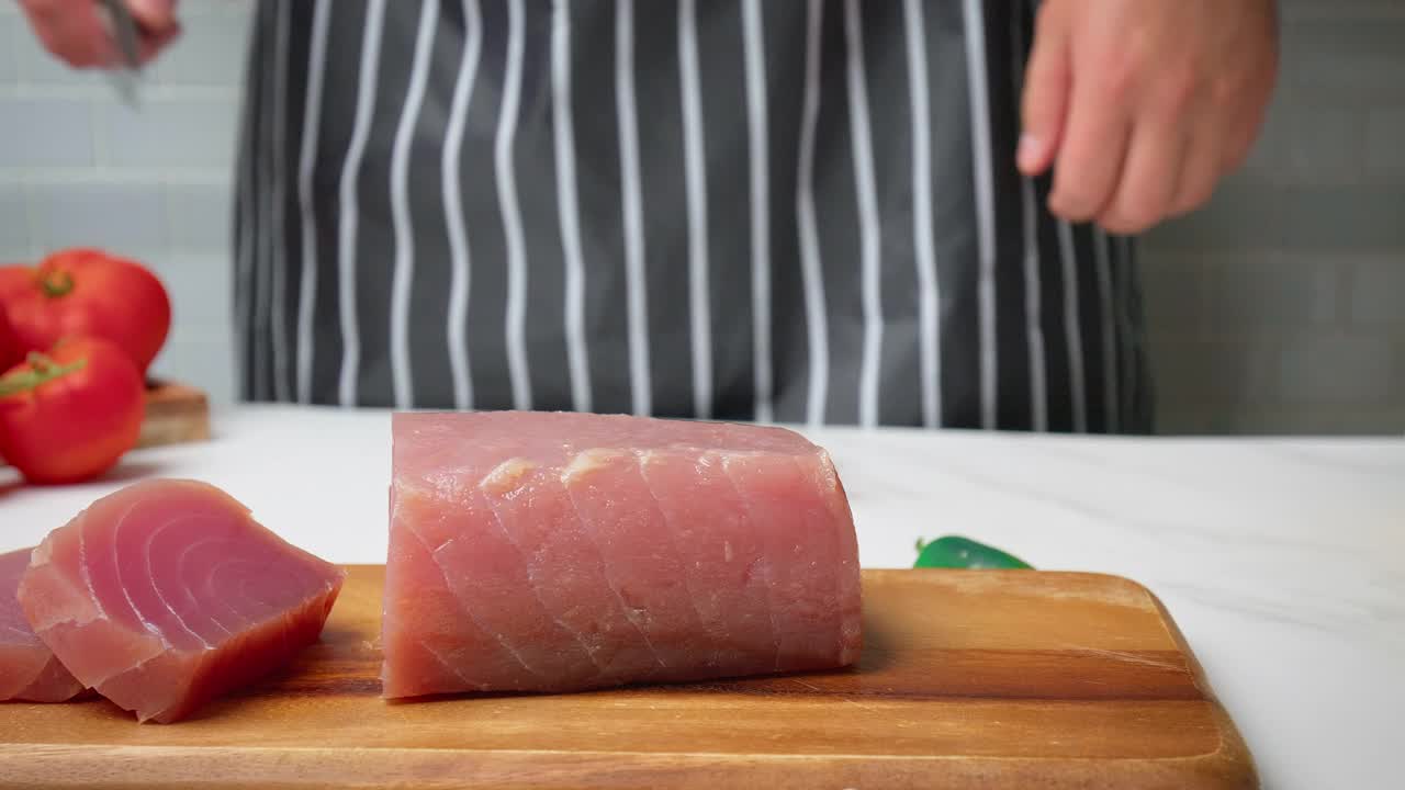 厨师将桌上的生金枪鱼黄鳍金枪鱼切成4K大小的大牛排。视频下载