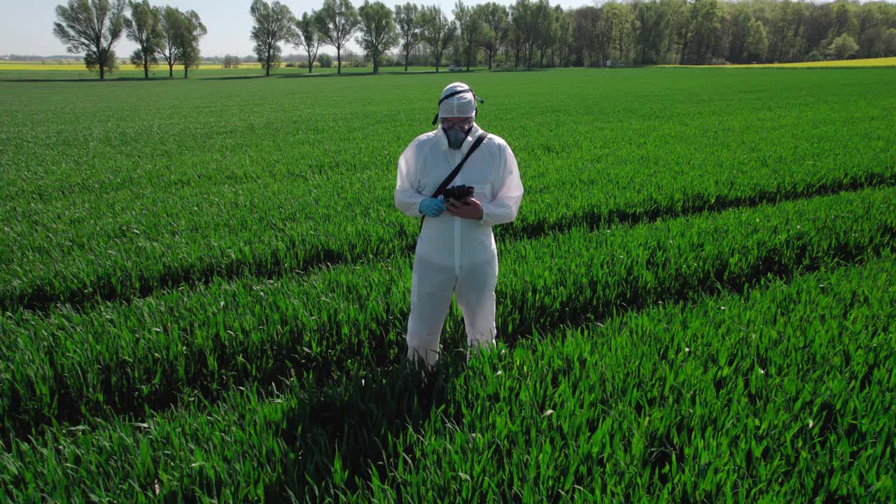 在一片麦田里，一个穿着防护服的农场工人正在进行作物试验。视频素材