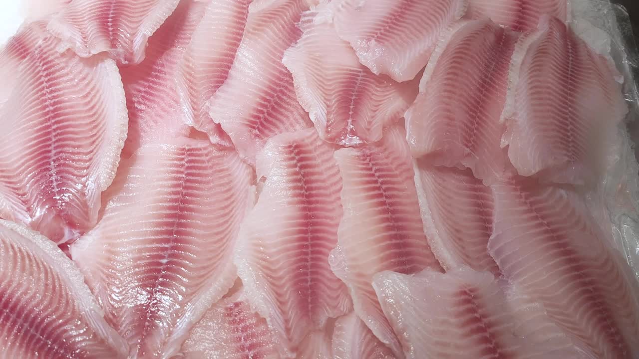 新鲜的罗非鱼片躺在商店的冰柜上，上面有冷却喷雾视频下载