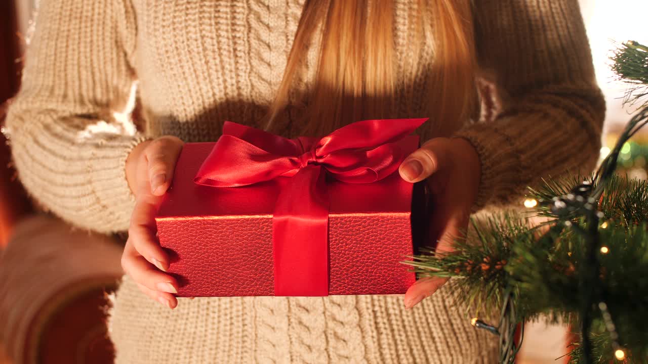 近距离4k镜头的年轻女子打开红盒子的礼物和看里面。圣诞节或新年的完美照片视频下载
