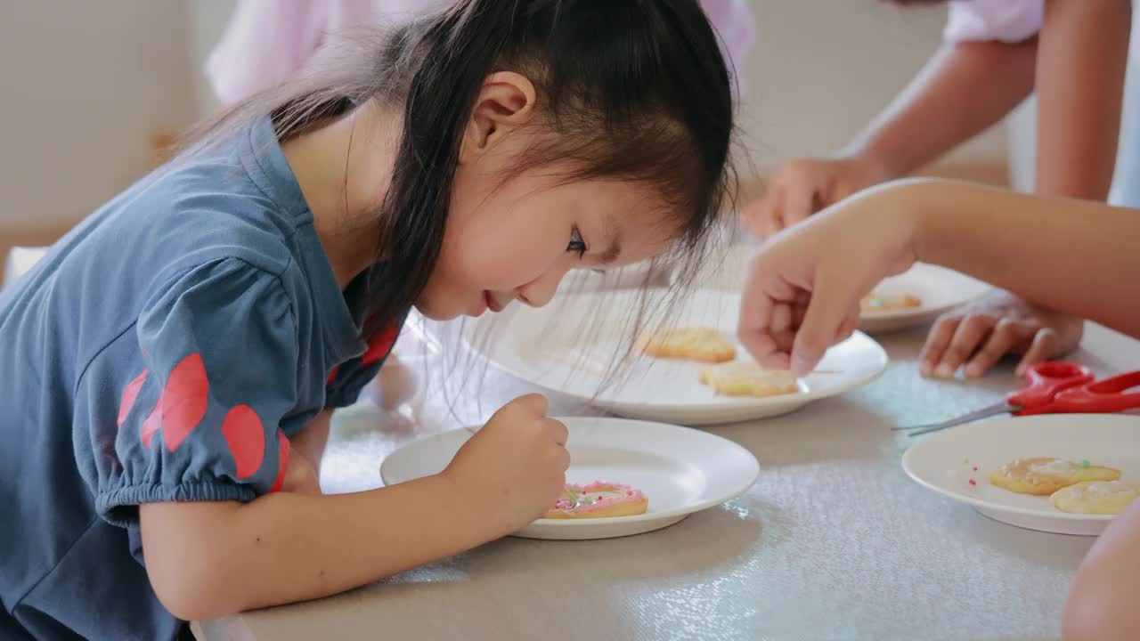 亚洲小女孩和朋友们一起为派对装饰饼干。DIY自制儿童艺术和工艺概念。视频下载