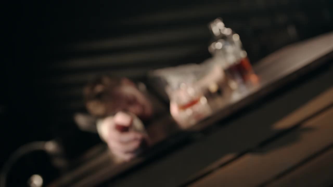一个悲伤的喝醉了的经理在一间黑屋子里倒在波旁威士忌后面的桌子上睡着了视频下载