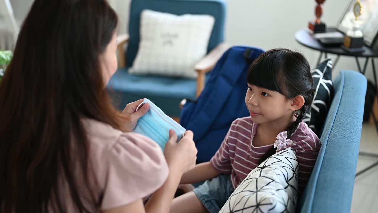 亚洲母亲帮助女儿戴上口罩保护新冠肺炎疫情视频下载